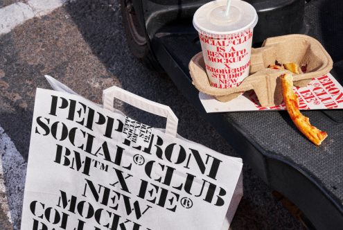 Mockup of a branded paper bag, drink cup, and pizza slice on a table, showcasing a bold font design for restaurant packaging. Ideal for designers. Graphics.