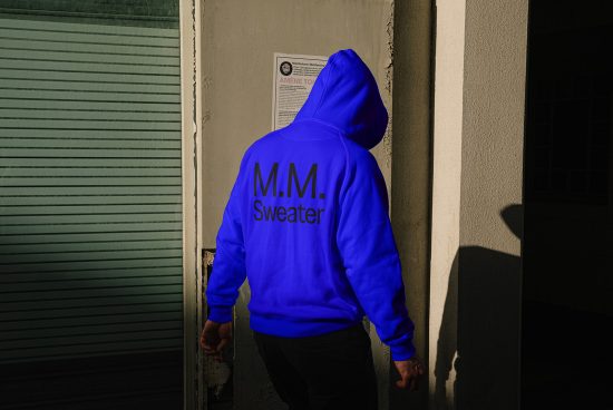 Back view of a person wearing a blue hoodie with black M.M. Sweater text. Ideal for apparel mockup designs. Keywords hoodies, apparel mockups, graphic design
