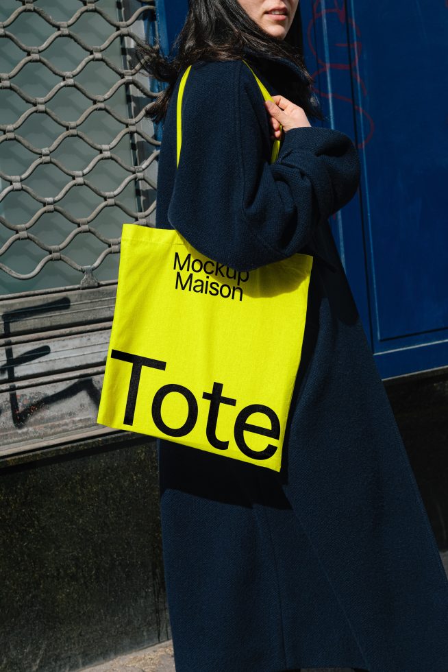 Woman carrying a yellow tote bag featuring Mockup Maison design. Perfect for graphic designers searching for tote bag mockups and showcasing branding projects.