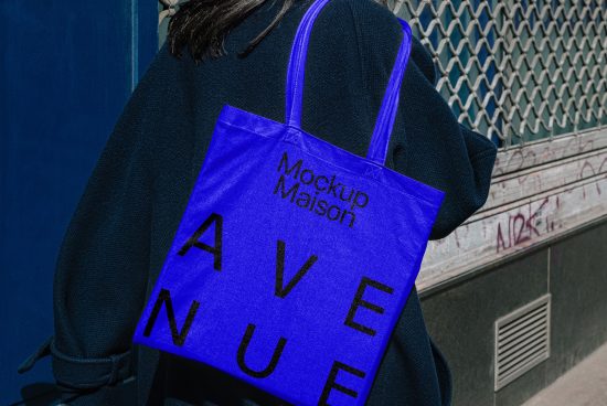 Mockup of a blue tote bag with black text design over a person's shoulder. Suitable for graphic designers and branding purposes. Ideal for templates and mockups.
