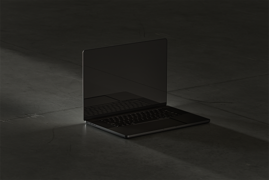 Modern open laptop mockup with blank black screen on dark concrete floor. Perfect for showcasing UI UX designs web templates and app interfaces. High-resolution graphic.