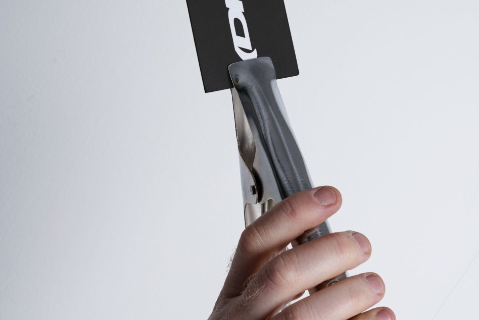 Hand holding pen with black label mockup against light background