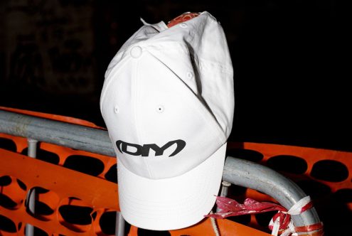 White DIY baseball cap on a metal fence with orange construction mesh background ideal for designers creating mockups branding templates or graphic projects