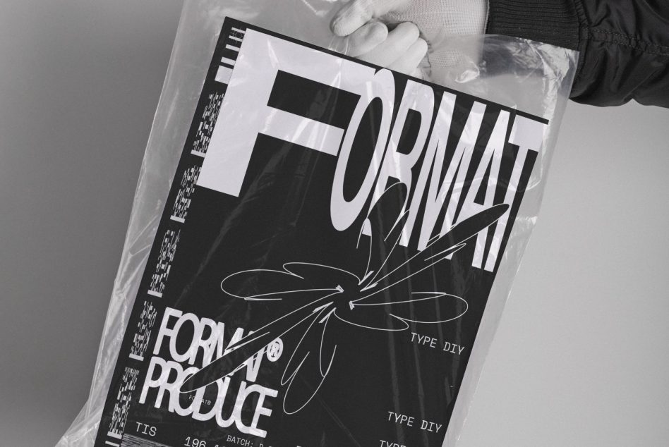 Hands holding glossy black magazine with bold typography in plastic wrap