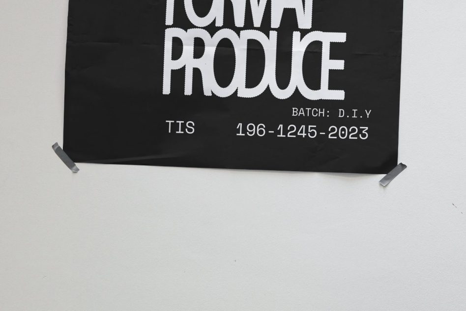 Black poster mockup with bold white text taped to gray wall, showcasing TIS FORMAT PRODUCE, batch: D.I.Y, perfect for design presentations and graphic templates