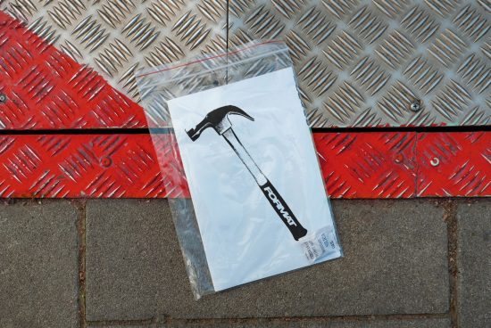 Graphic print of a hammer in a plastic bag on a metal and concrete surface. Ideal for design templates mockups prints digital assets for designers, SEO keywords.