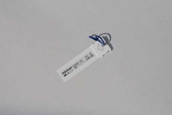 White product label with blue string on plain background suitable for use in mockups templates graphics and designer projects. High resolution image.