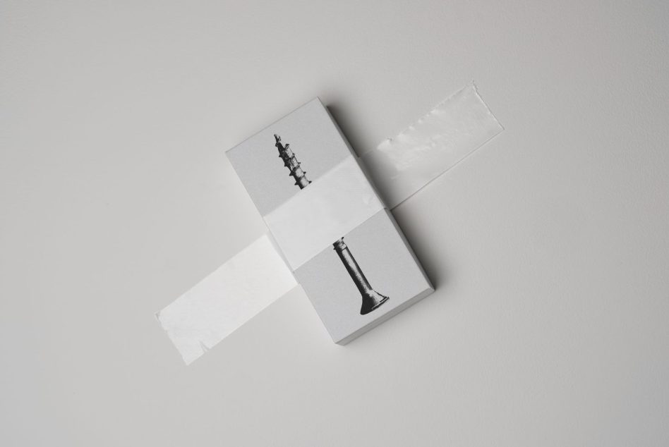 Minimalist packaging mockup with a silver box secured by white tape featuring a black screw graphic, perfect for showcasing branding or design templates.