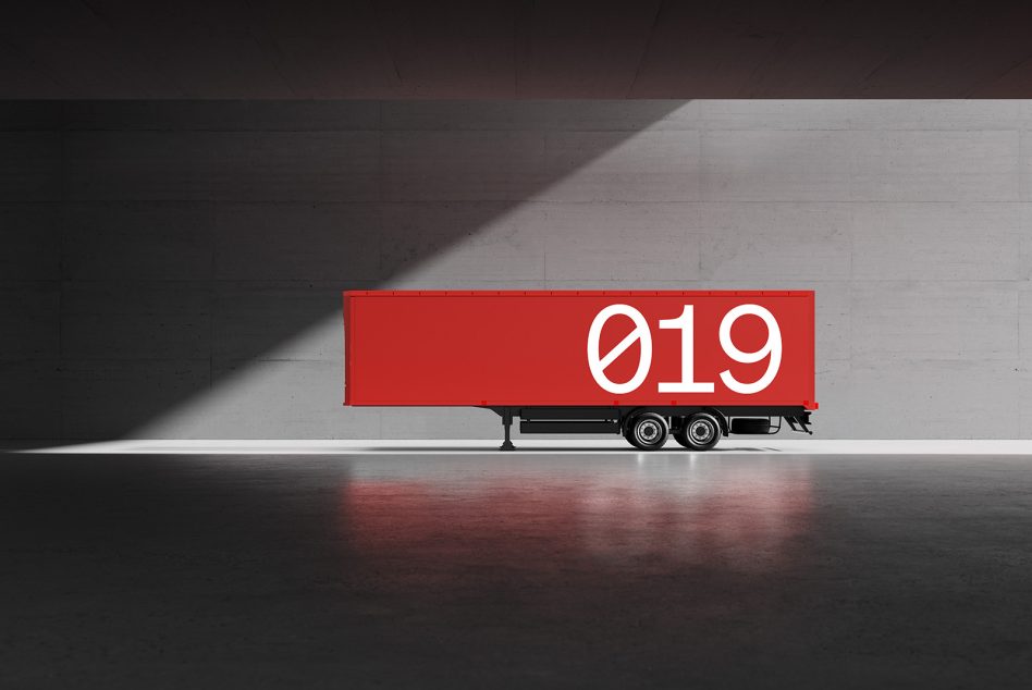 Red semi-trailer mockup against concrete wall with large white numbers 019. Ideal for designers creating realistic transport graphics and advertisement templates.