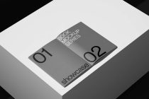 Open gray hardcover book mockup showing two volumes, displayed on white platform