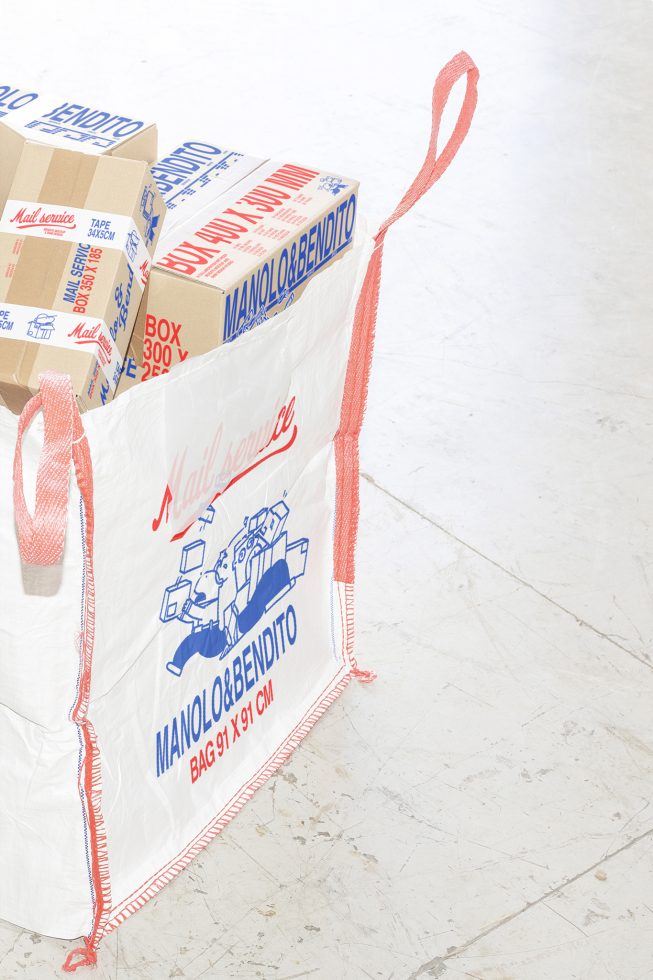 Large white bag with red accents containing boxes with blue and red text on a light floor. Keywords: packaging mockup, delivery, postal, design asset, ecommerce.