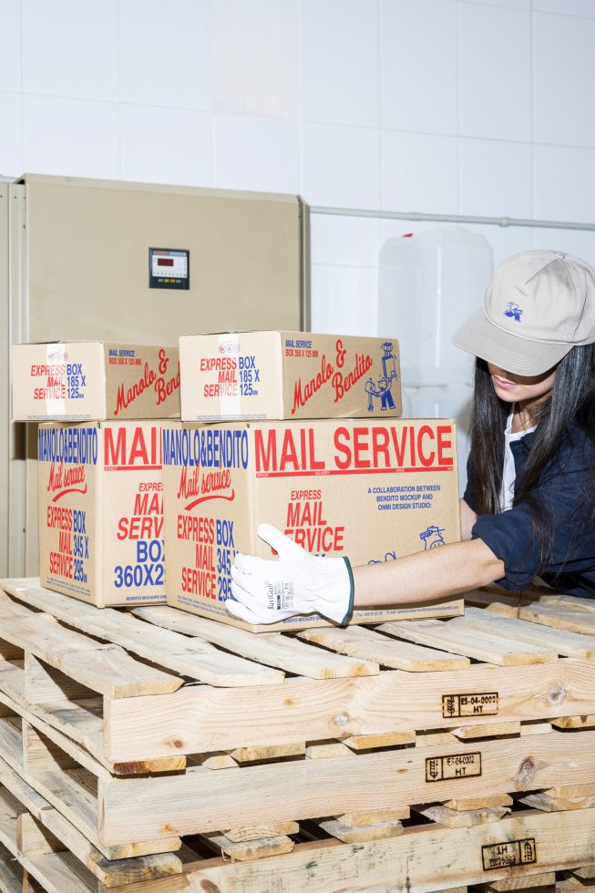 Warehouse packaging mockup with mail service boxes on wooden pallets, featuring branded express mail boxes carried by worker in protective gloves and cap.