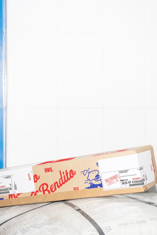 Realistic delivery box mockup leaning against white tiled wall, perfect for showcasing packaging design. Ideal for designers in need of high-quality mockups.