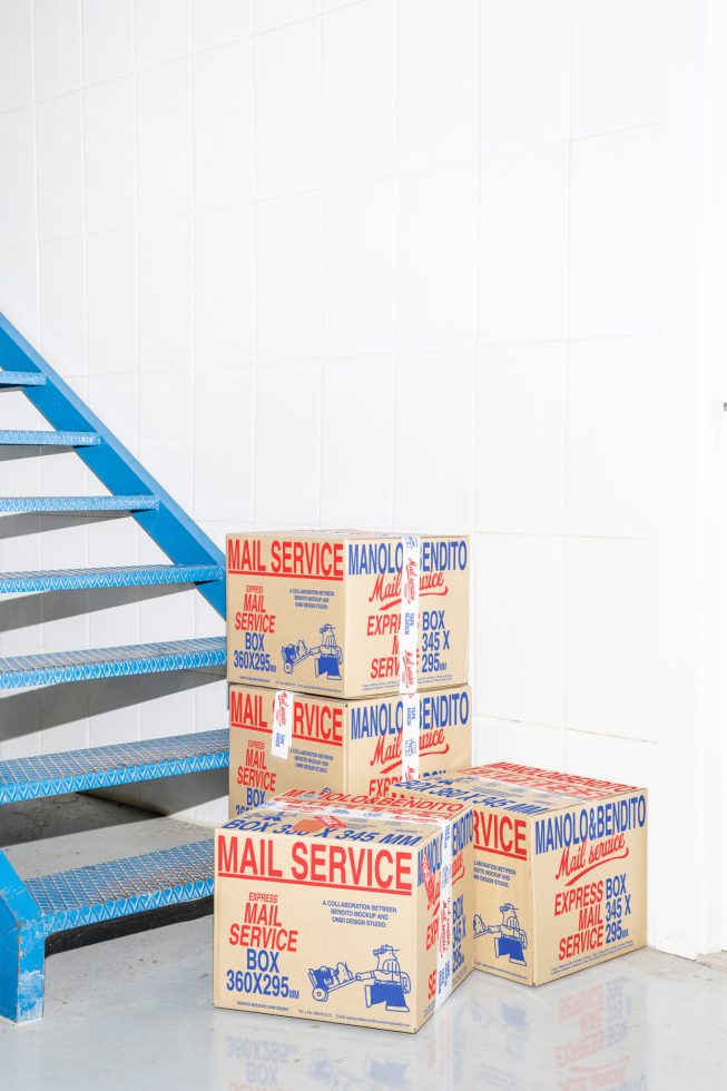 Stack of four vintage mail service boxes in a minimalist white room beside a blue staircase. Perfect for mockups, graphic design, branding, packaging.