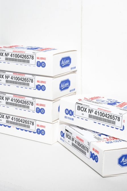 Stacked white small shipping boxes with blue logos, red text, barcode labels arranged in rows