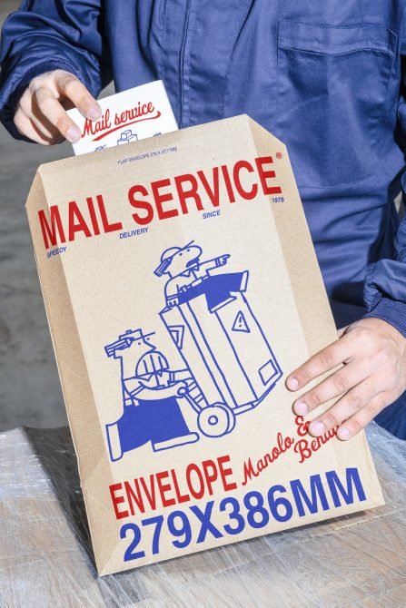 Mockup of a mail service envelope with 279x386mm dimensions held by a person. Graphic design features vintage illustrations and bold typography suitable for designers.