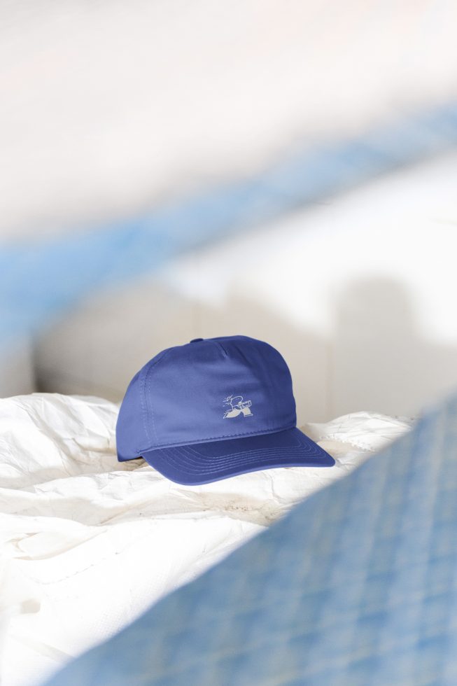 Blue baseball cap mockup with white logo lying on crumpled fabric. Perfect for designers seeking cap graphics, fashion accessories, and apparel mockups.