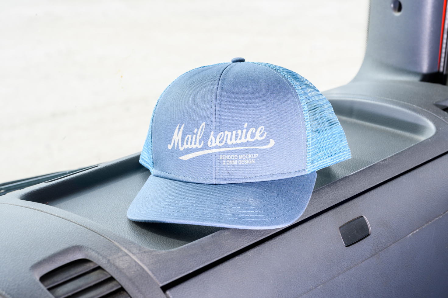 Blue trucker cap mockup with Mail Service text placed on a car dashboard; ideal for apparel design presentations. Keywords: apparel mockup, trucker cap design.