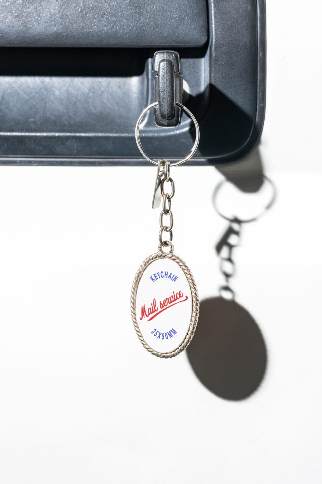 Close-up of a key in a lock with a metal keychain displaying Mail service text with dimensions 35x50mm, ideal for mockup, graphic design, and template projects.