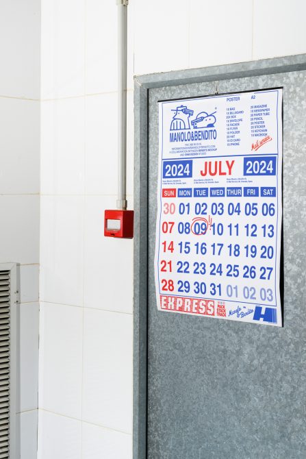 Studio wall calendar mockup for July 2024 displayed on a metal door in a minimalist setting. Ideal for designers needing mockup templates with clean design.