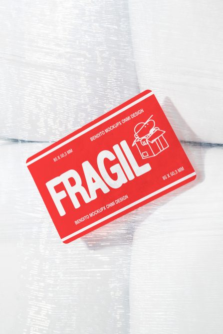 Red Fragile tag mockup with dimensions 85 x 50.3 mm placed against white textured background. Ideal for graphic designers, packaging mockups, digital assets.