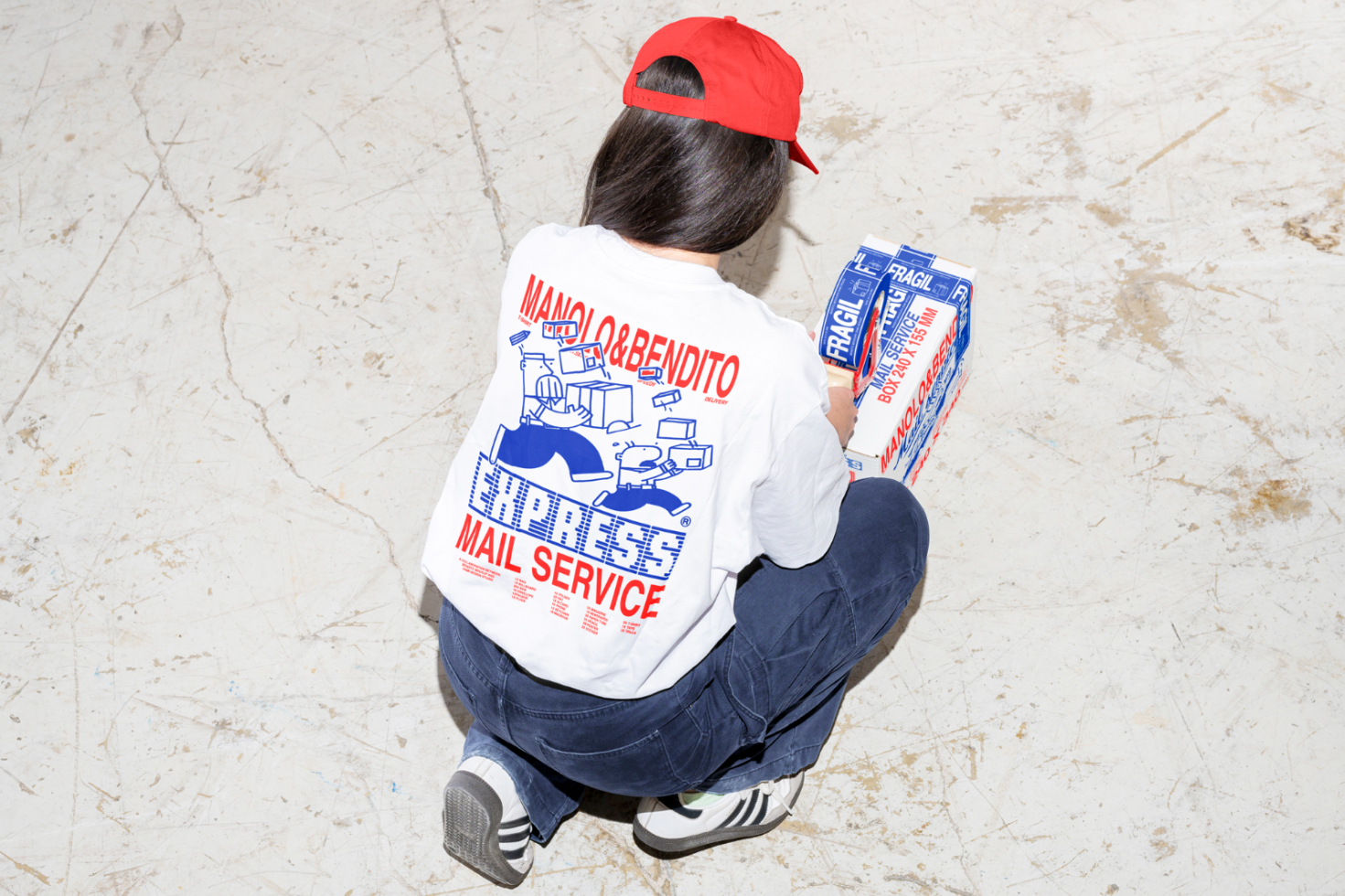 Person wearing red hat and Express Mail Service t-shirt holding a box. Ideal for packaging design mockups, branding graphics, and mailing templates.