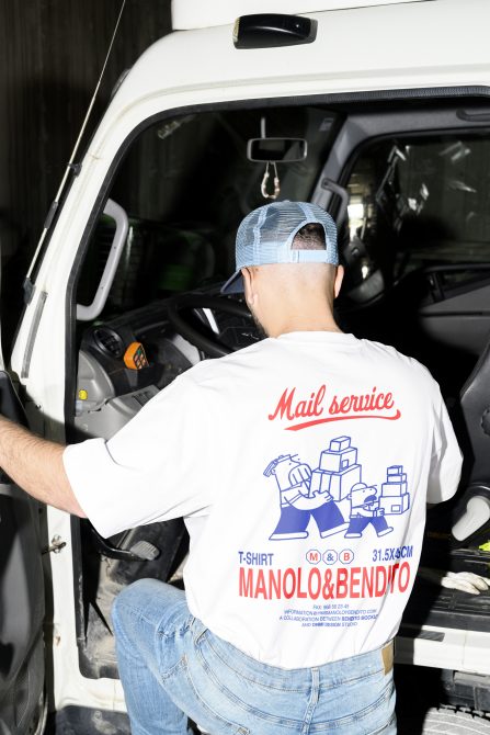 Mockup of a person wearing a custom print white t-shirt and blue cap. The back of the t-shirt has a mail service graphic. Keywords: mockups, apparel, design