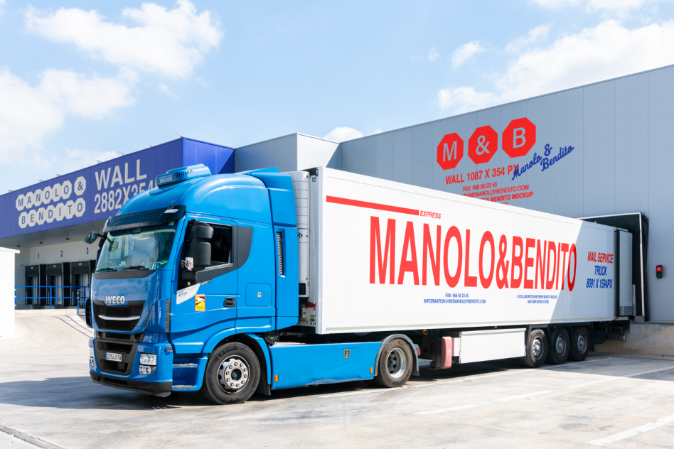 Blue truck and trailer at a logistics warehouse loading dock with branding Manolo and Bendito digital assets mockup. Keywords: mockups, graphics, templates.