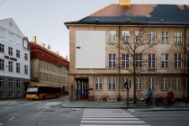 Blank billboard on historic European building facade with bus, cyclists, pedestrians visible
