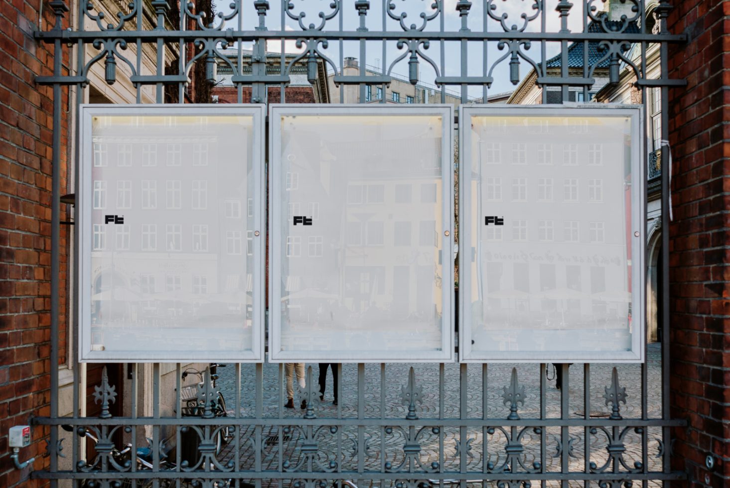 Mockup of three blank outdoor posters on a wrought iron fence in an urban setting ideal for showcasing advertising, designs, and graphics to designers.