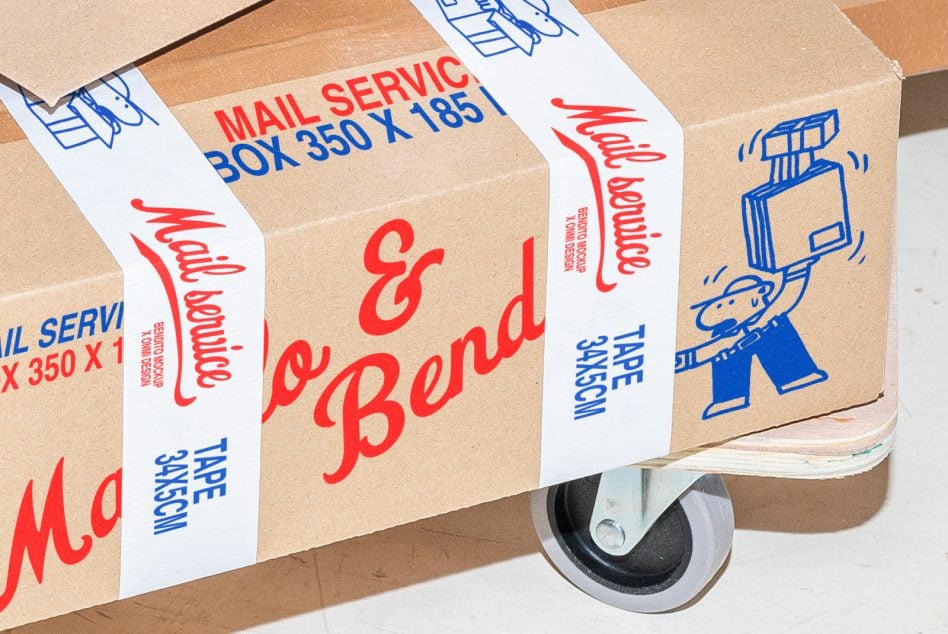 Cardboard box mockup with red Manolo Bendito mail service design on tape