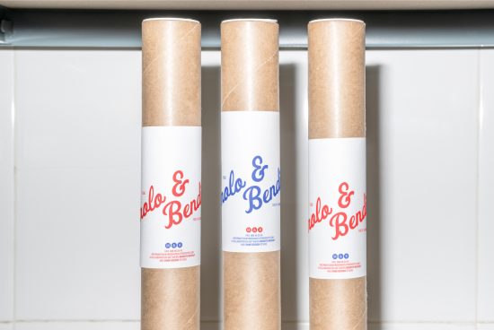 Three brown cardboard tube mockups with white labels displaying the text Polo & Bendo in red and blue, standing upright on a white tiled background.