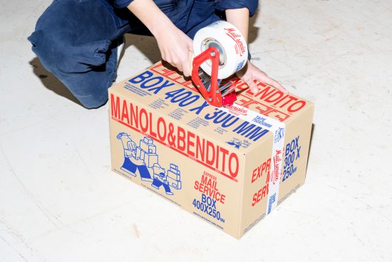 Person taping a Manolo&Bendito cardboard box with branded packaging tape. Suitable for mockups and retail graphics. Keywords: mockups, packaging, branding, retail.