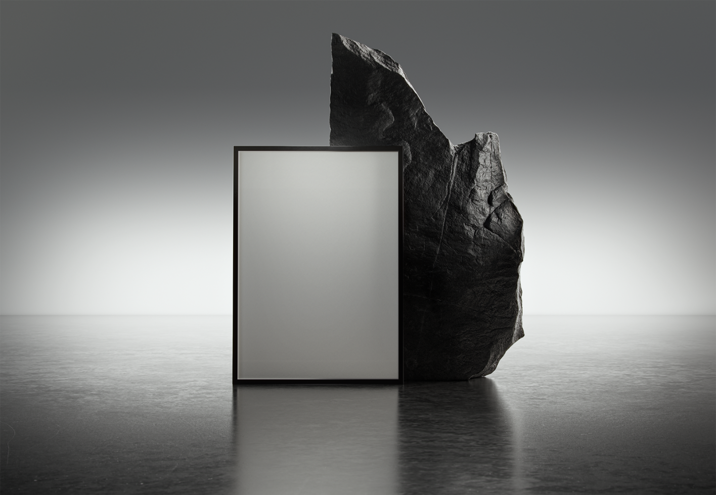 Mockup of a blank vertical poster with black frame standing on a reflective surface against a large dark rock in a minimal studio background