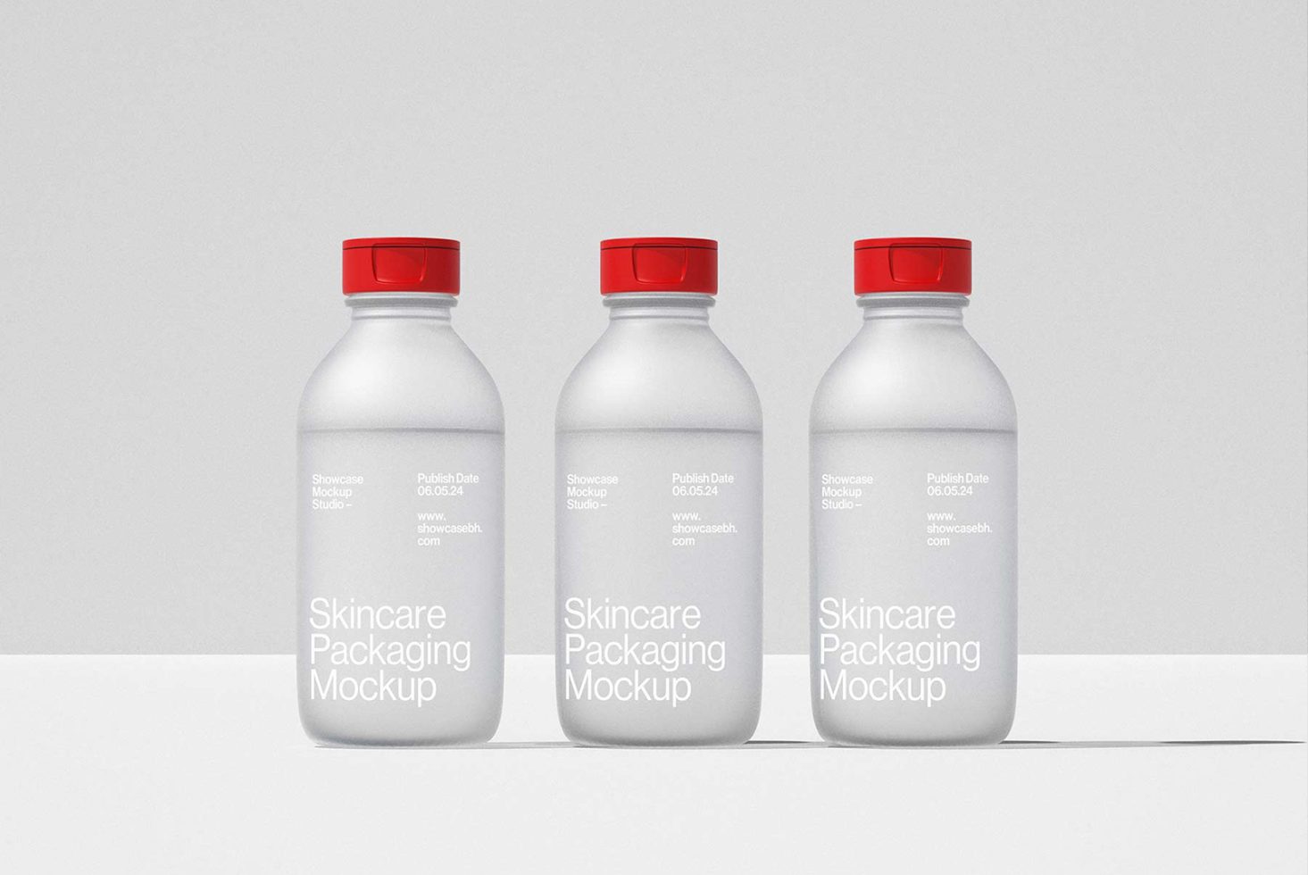 Three white skincare packaging bottles mockup with red caps, for designers, isolated on grey background. Ideal for showcasing product packaging design.