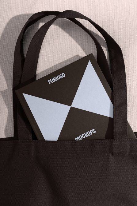 Book with geometric design and text Furioso Mockups partially tucked in black tote bag perfect for showcasing mockups templates digital assets for designers.