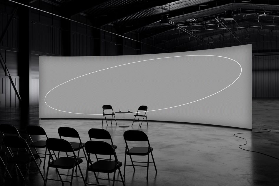 Modern conference mockup with chairs facing curved screen backdrop in industrial setting, suitable for digital designers visual assets or event presentation templates.