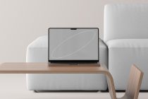 Laptop mockup on wooden desk with white sofa, minimal line art on screen