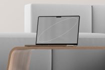 Laptop on light gray sofa showing neutral screen with simple oval outline