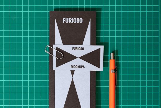 Mockup template with black leaflet labeled Furioso, attached with paperclip, orange pen on green cutting mat; ideal for designers branding presentations