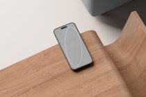 iPhone mockup on wood showing blank gray screen with minimalist line design