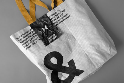 Canvas tote bag mockup with yellow handles featuring large ampersand symbol. Ideal for designers creating branding, marketing, and packaging presentations.