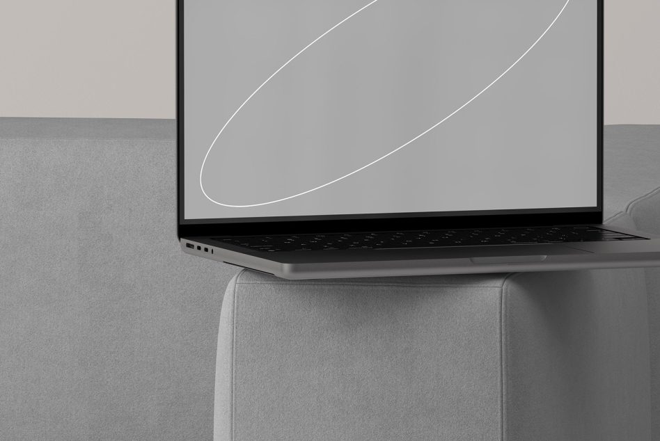 Laptop balanced on gray chair with outline design visible on screen