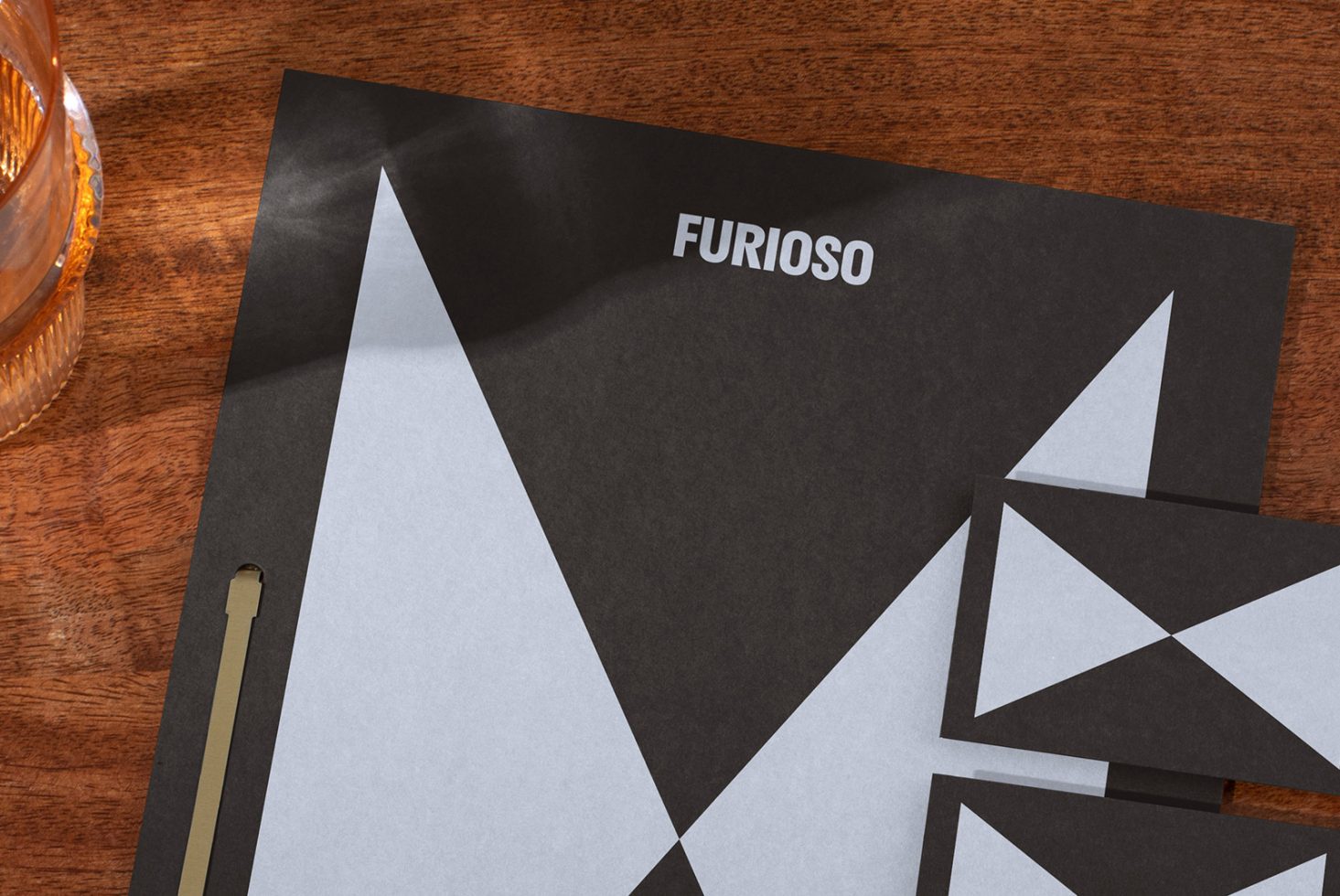 Professional branding mockup featuring geometric black and white letterhead and business cards on a wooden table suitable for graphic design presentations