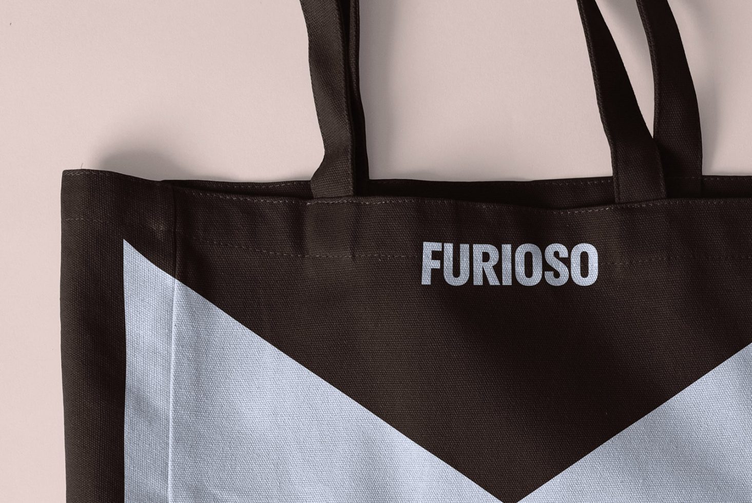 Close-up of a black fabric tote bag with light blue geometric design and text reading Furioso. Perfect for designers. Mockup, digital asset, graphic design.