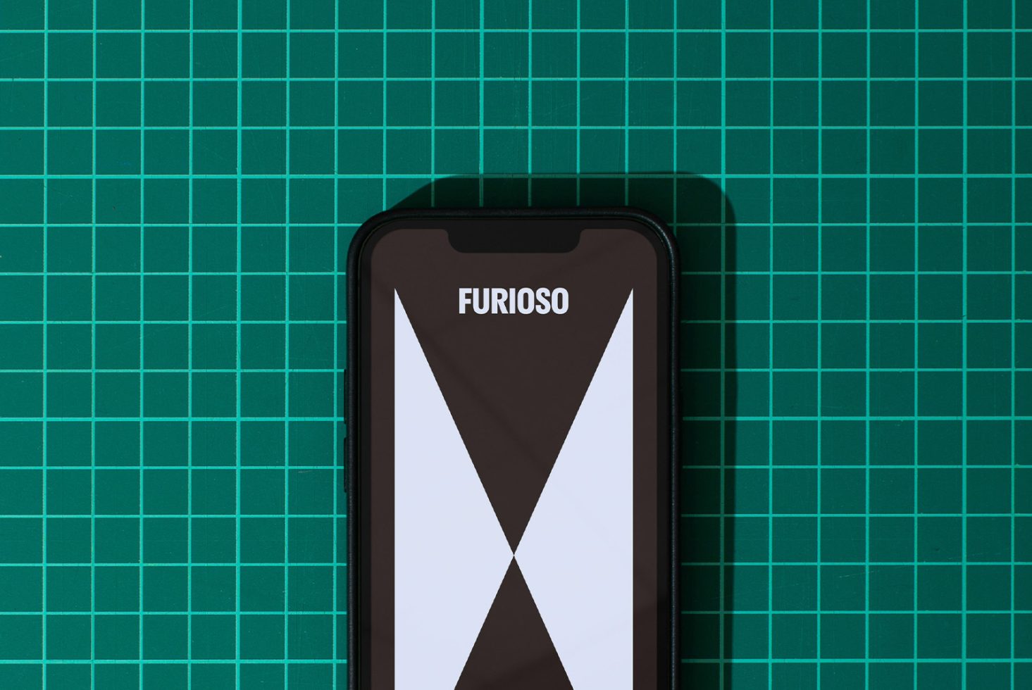 Mockup of a smartphone on a green cutting mat. Design on screen shows bold text Furioso and geometric shapes. Perfect for showcasing digital assets, templates.