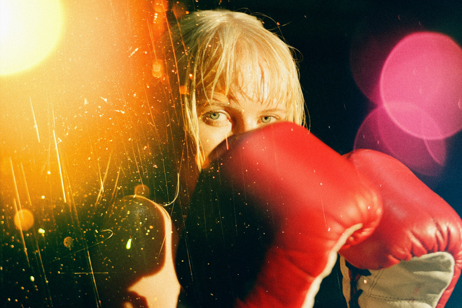 Vibrant photo of a female boxer in action with red gloves and light effects for use in digital graphics, templates, and design mockups.