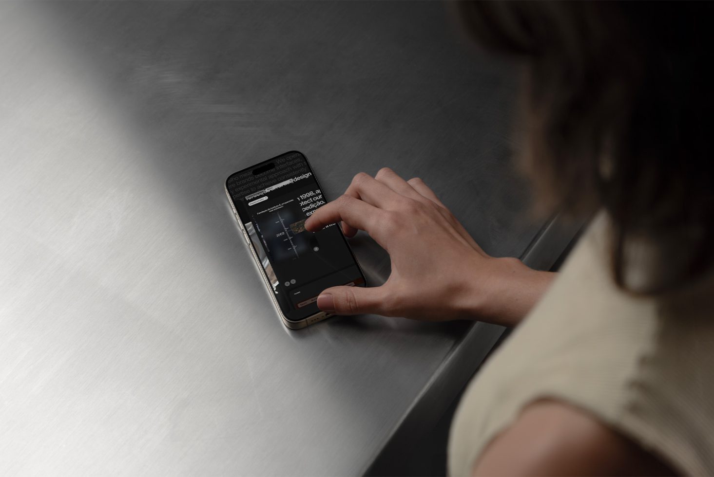 Woman using iPhone on a stainless-steel table suitable for Mockups with editable open app screen for digital assets designers targeting user interface design