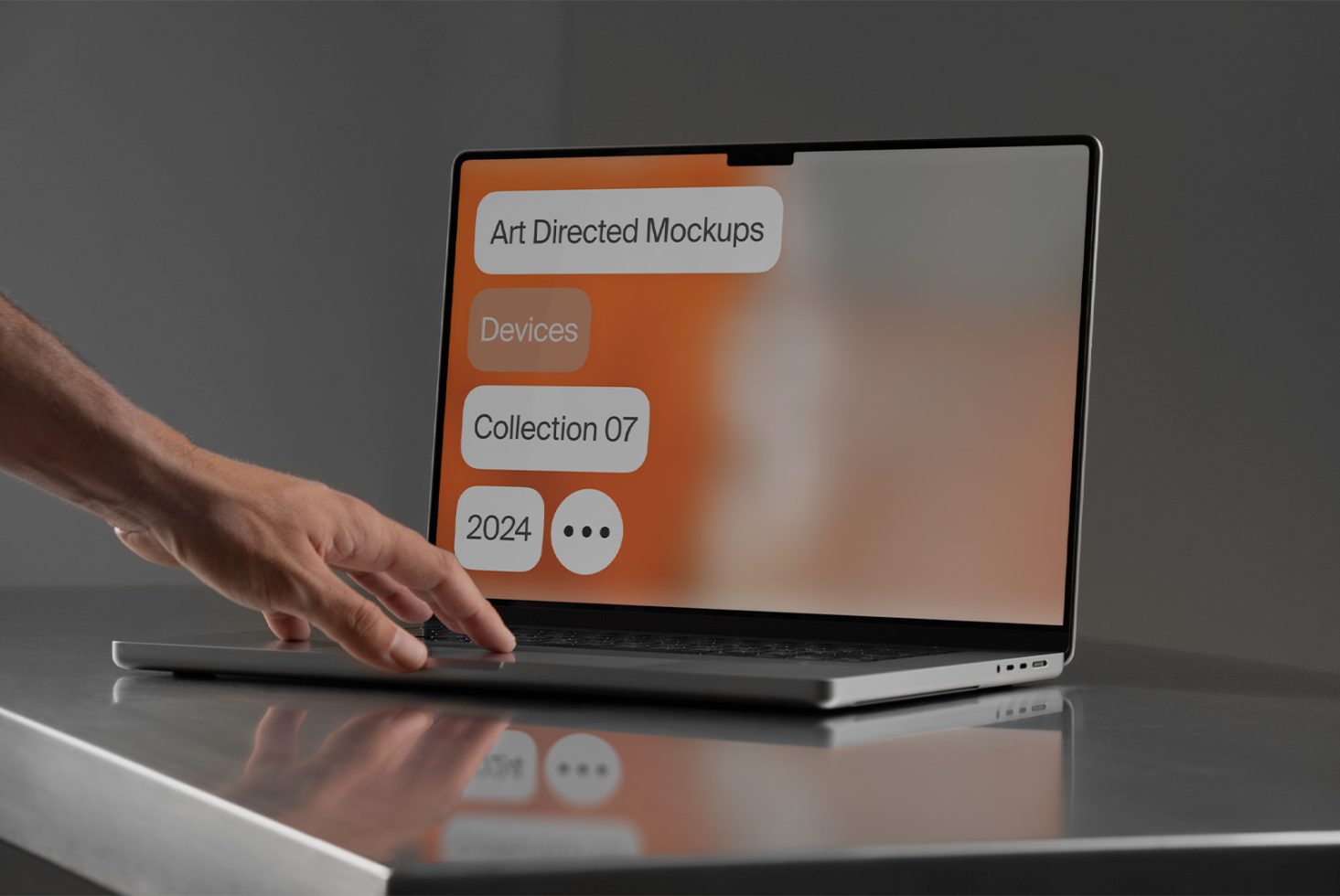 Laptop with Art Directed Mockups Devices Collection 07 2024 on screen, set on a table with a hand interacting. Ideal for showcasing device mockups.