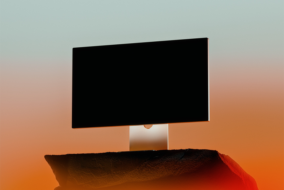 Wide screen monitor mockup. Black screen monitor on rocky surface against gradient orange and blue background. Ideal for showcasing digital assets templates.